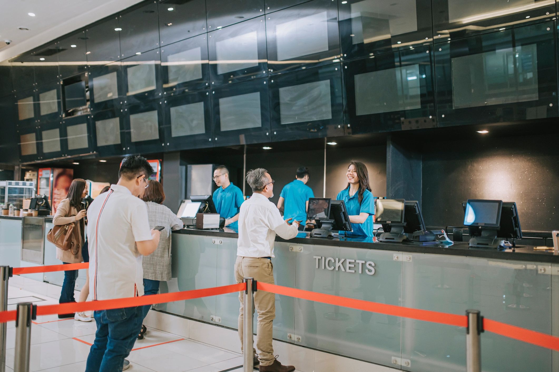 People queuing at a cinema counter with popcorn and drinks