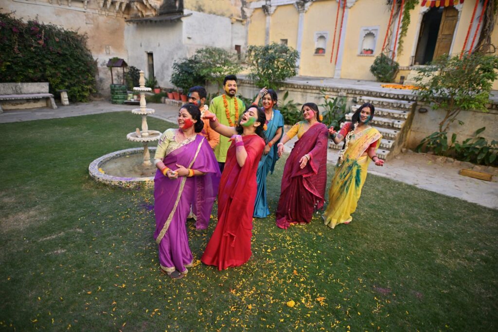 Group of Indian men and women in traditional wear dancing and celebrating Holi festival in the courtyard of a palace in Rajasthan