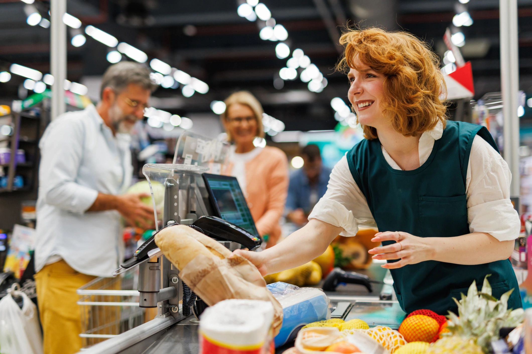 Cashier scanning groceries at a supermarket checkout counter