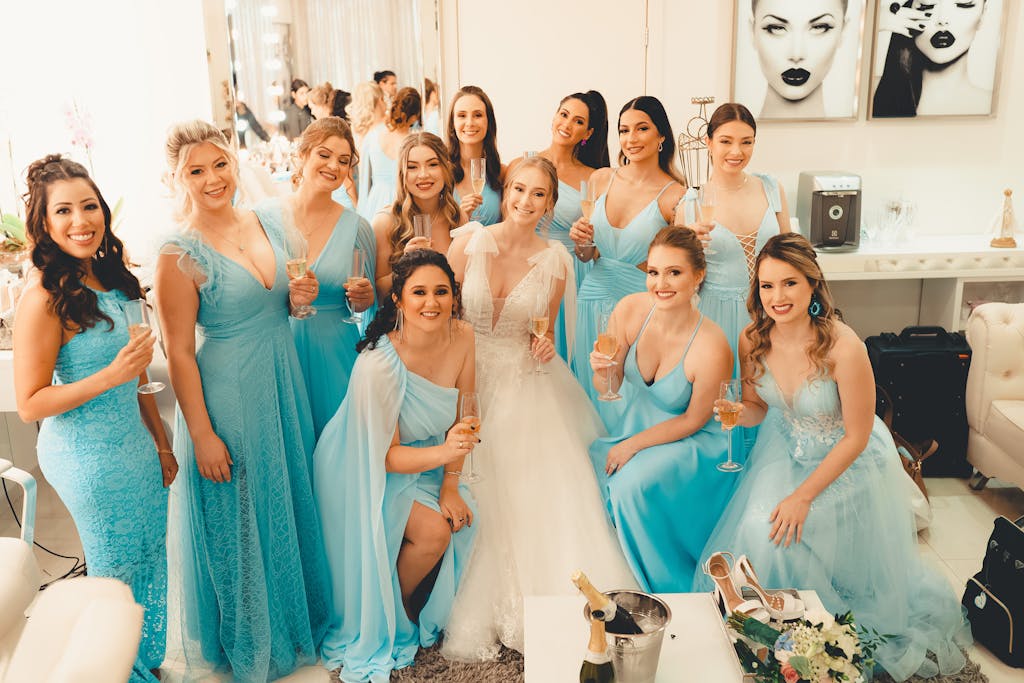 A joyful bridal party in blue dresses celebrating with champagne indoors.