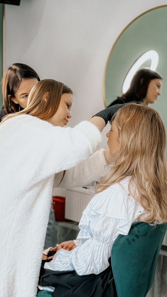 A makeup artist applying cosmetics to a woman's face in a beauty salon.