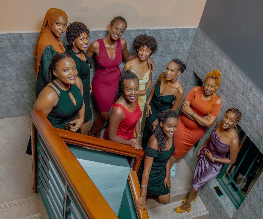 A vibrant group of diverse women posing on a staircase indoors, dressed elegantly.